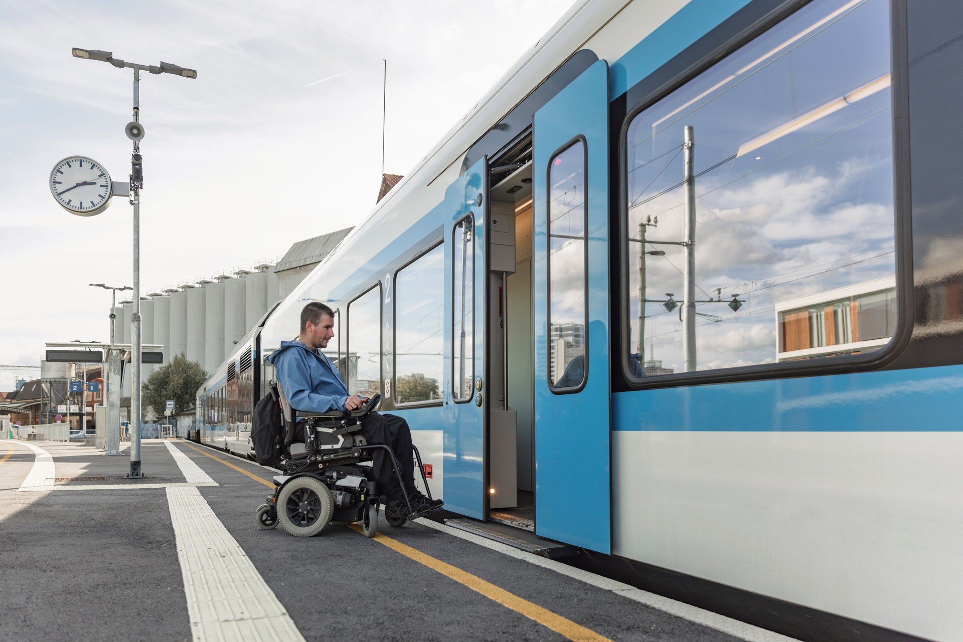 Man with a physical disability, an electric wheelchair user entering a train