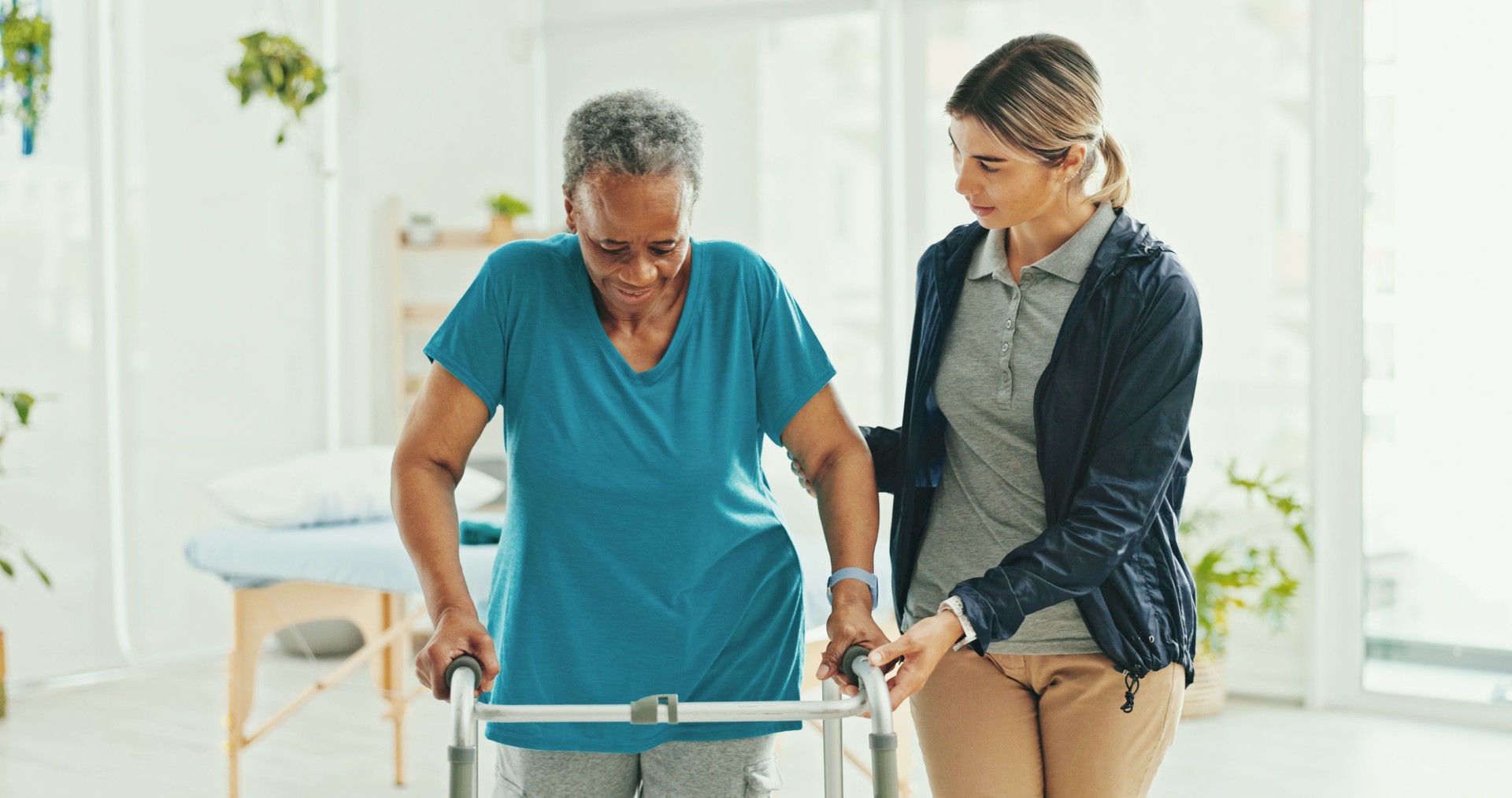 Senior woman, physiotherapist and walker with support, recovery and helping hand with steps at hospital. Doctor, frame and person with disability, rehabilitation or progress with balance at clinic