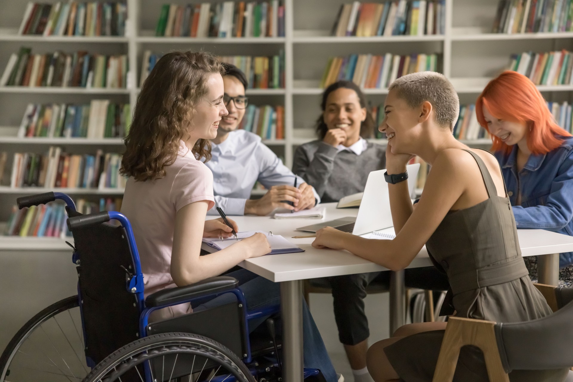 Young student with disability cooperating on project with college friends