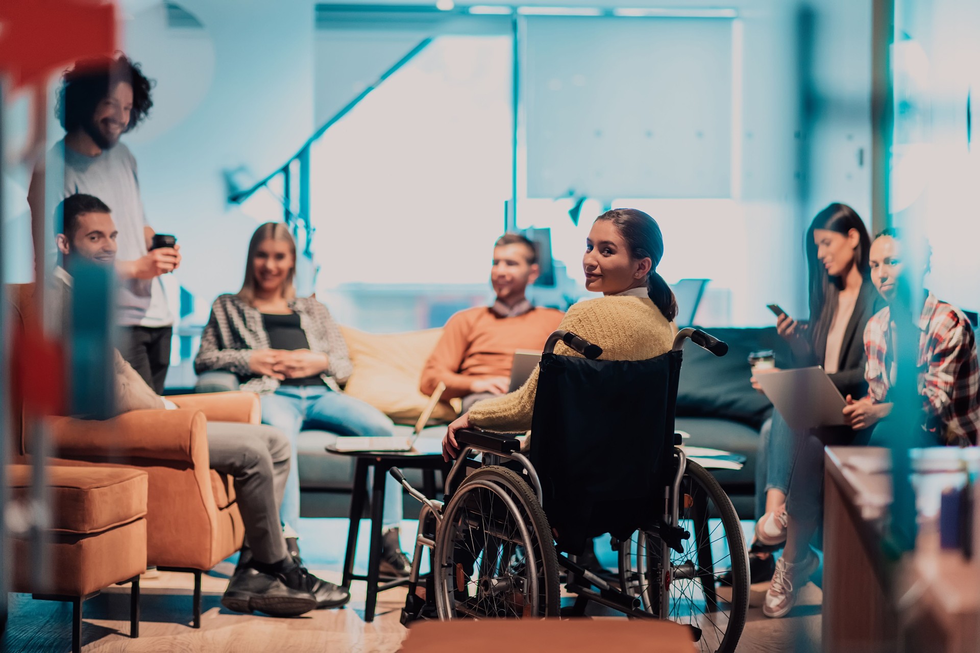 Businesswoman in wheelchair having business meeting with team at modern office. A group of young freelancers agree on new online business projects